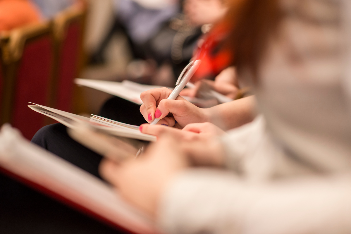 people sitting at a conference taking notes